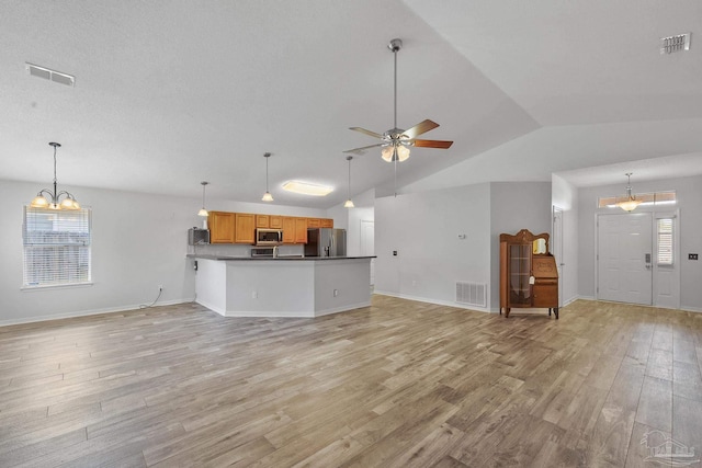 unfurnished living room featuring ceiling fan with notable chandelier, lofted ceiling, plenty of natural light, and light wood-type flooring