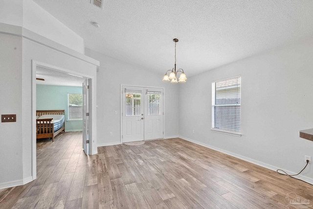 interior space with french doors, hardwood / wood-style floors, a notable chandelier, and a textured ceiling