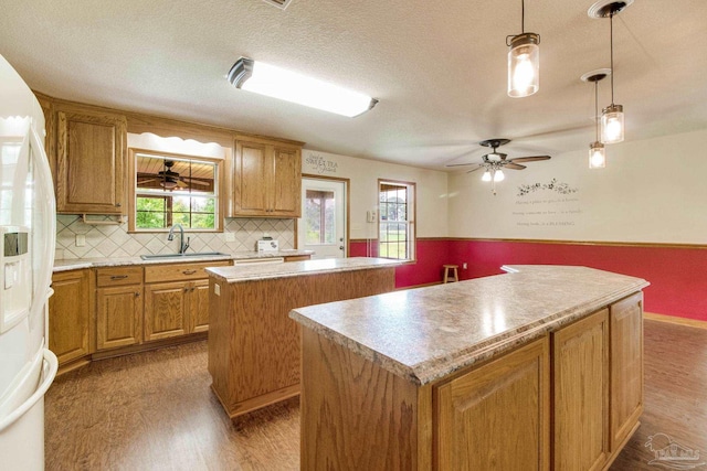 8206 Chumuckla Hwy, Pace, FL 32571 - kitchen featuring a kitchen island, a sink, wood finished floors, white refrigerator with ice dispenser, and a textured ceiling