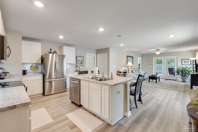 kitchen featuring light wood finished floors, white cabinets, a sink, visible vents, and appliances with stainless steel finishes