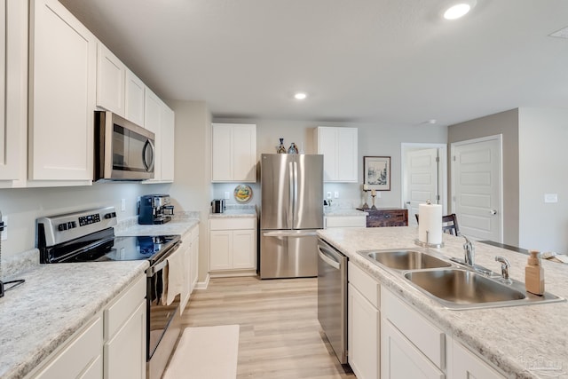 kitchen with stainless steel appliances, light wood-style flooring, a sink, recessed lighting, and white cabinetry