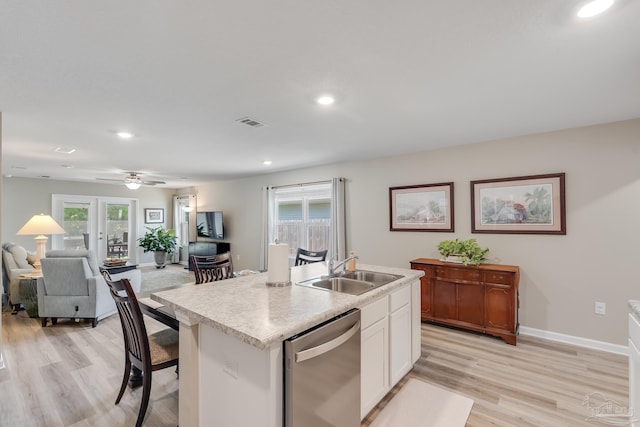 kitchen featuring stainless steel dishwasher, a sink, light wood-style floors, open floor plan, and white cabinetry