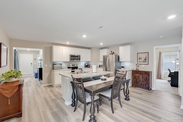 dining space featuring baseboards, light wood finished floors, visible vents, and recessed lighting