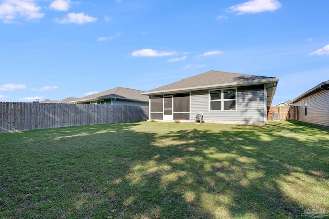 back of house with a shingled roof, a fenced backyard, a sunroom, and a yard
