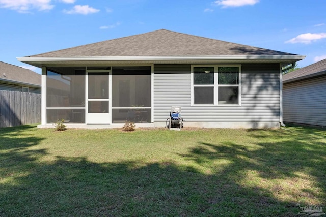 back of property with fence, a shingled roof, a sunroom, and a yard