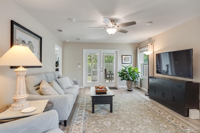 living room with ceiling fan, baseboards, visible vents, and light wood-type flooring