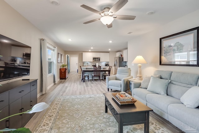 living area featuring ceiling fan, baseboards, light wood-style floors, and recessed lighting