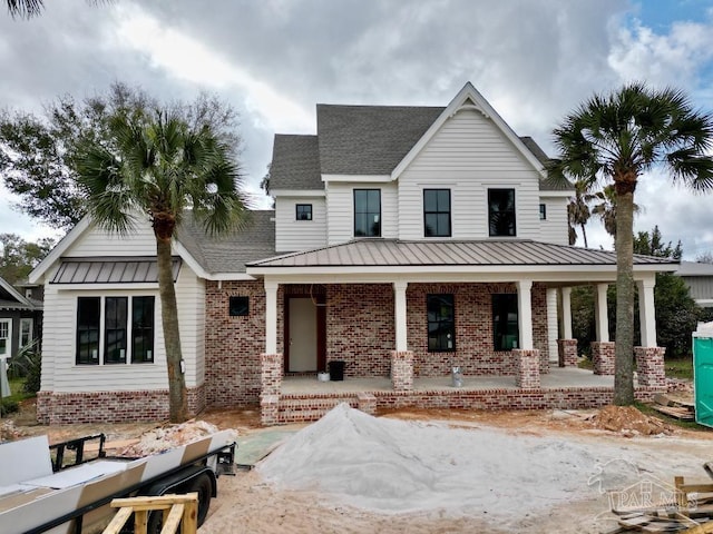 view of front of property featuring metal roof, brick siding, a porch, and a standing seam roof