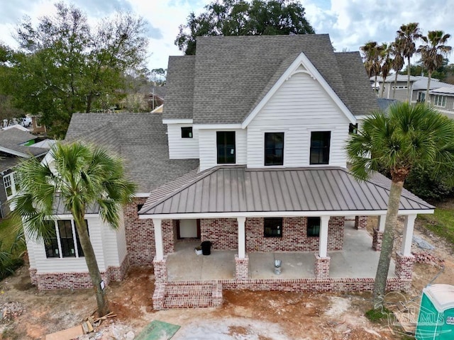 exterior space featuring brick siding, a shingled roof, and a patio area