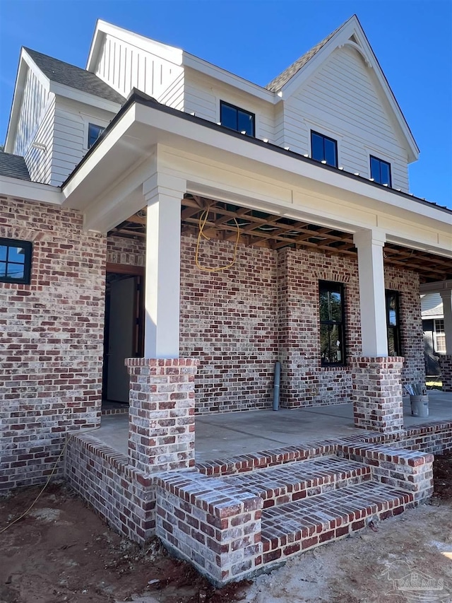 property entrance with brick siding and covered porch