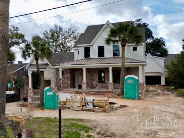 view of front of property with metal roof, brick siding, and dirt driveway