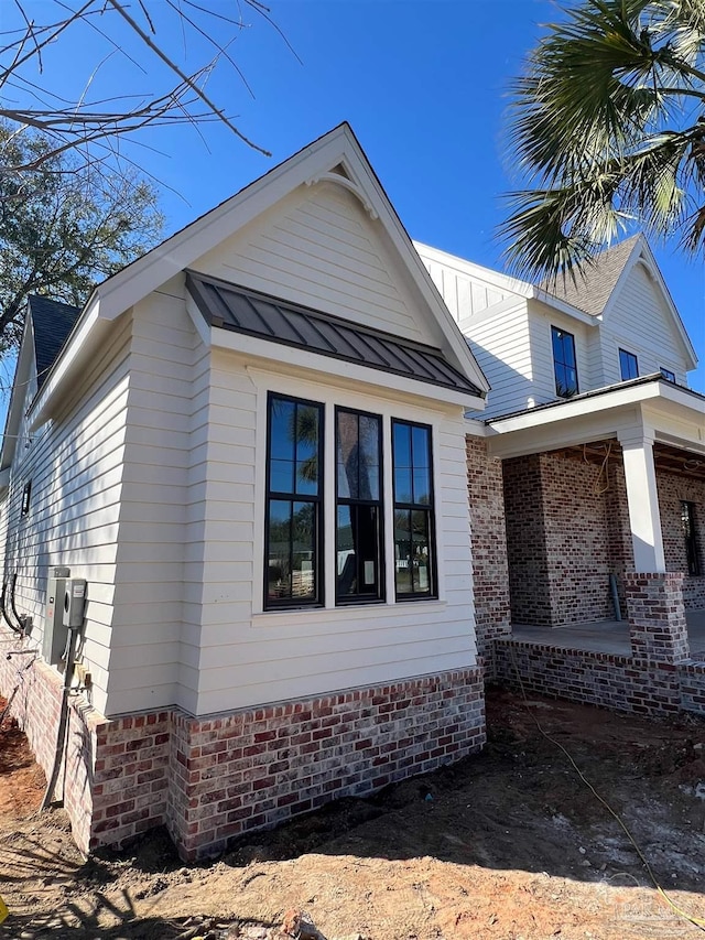 view of property exterior featuring a standing seam roof, a porch, and metal roof