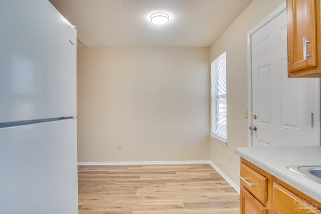 kitchen featuring a textured ceiling, white fridge, and light hardwood / wood-style flooring