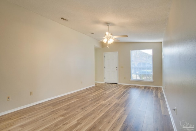 spare room with ceiling fan, a textured ceiling, and light wood-type flooring