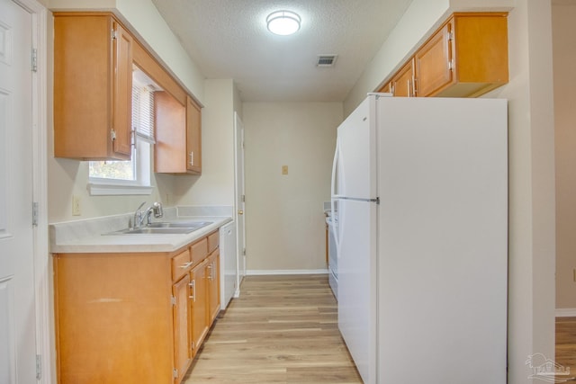 kitchen featuring a textured ceiling, sink, white appliances, and light wood-type flooring