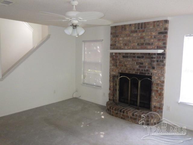 unfurnished living room featuring a brick fireplace and ceiling fan