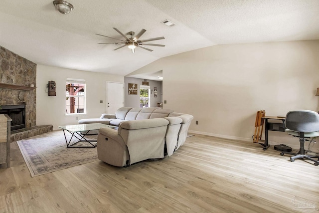 2661 Avenida De Sol, Navarre, FL 32566 - living area featuring lofted ceiling, a ceiling fan, light wood-style flooring, a textured ceiling, and a stone fireplace