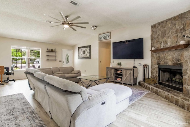 2661 Avenida De Sol, Navarre, FL 32566 - living room with light wood-type flooring, ceiling fan, a textured ceiling, a stone fireplace, and lofted ceiling