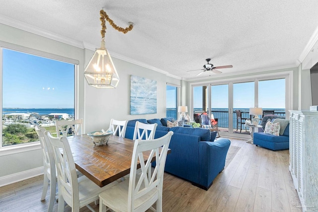 dining area with ornamental molding, light wood finished floors, and a water view