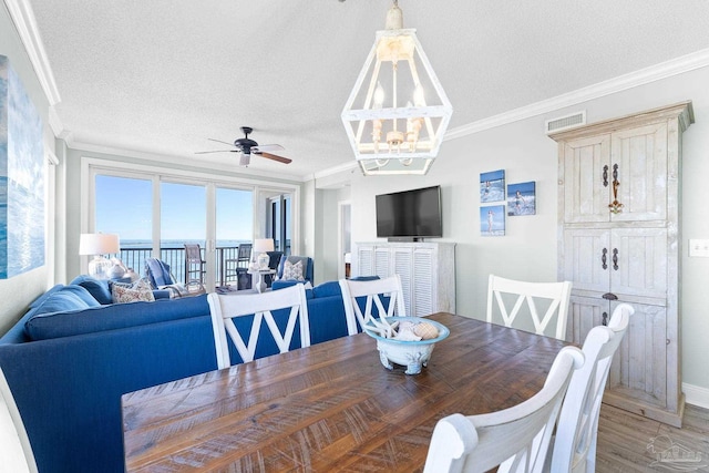 dining space with visible vents, crown molding, a textured ceiling, and wood finished floors