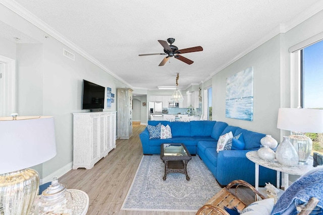 living area with ornamental molding, visible vents, light wood-style flooring, and a textured ceiling