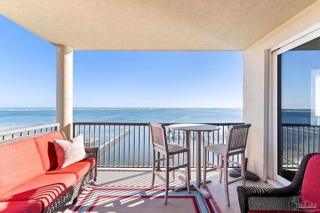 balcony with a water view and an outdoor hangout area