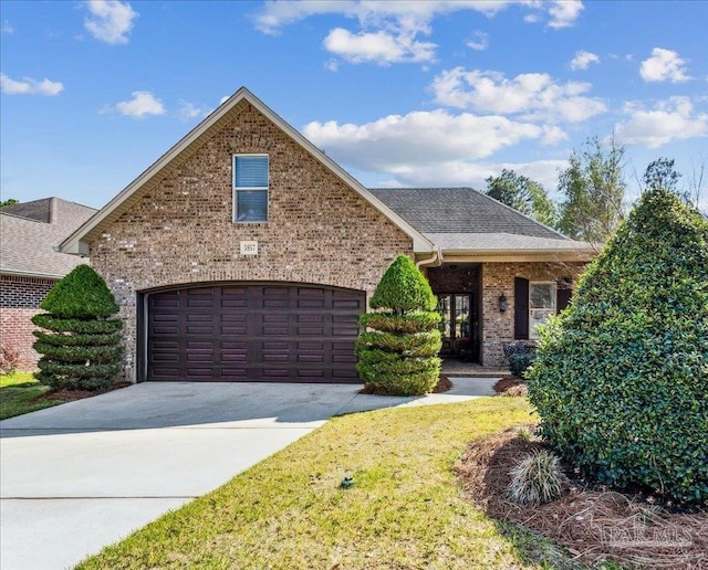 view of front of house featuring driveway, roof with shingles, a front yard, and brick siding