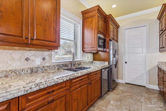 kitchen with appliances with stainless steel finishes, light stone countertops, a sink, and ornamental molding