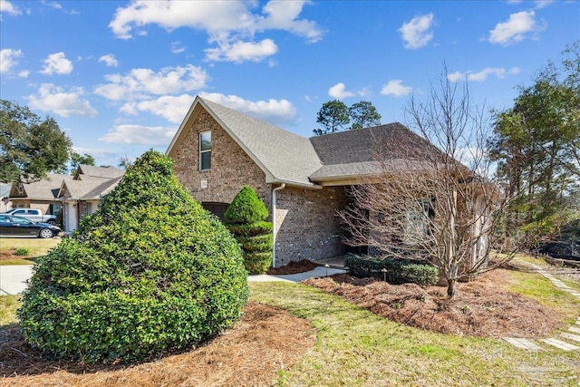 view of front of property featuring brick siding and roof with shingles