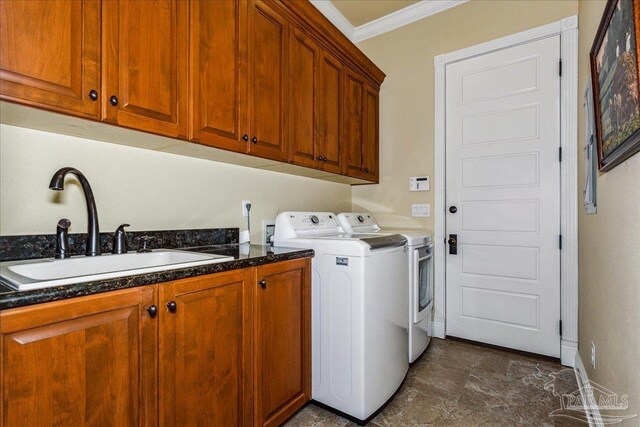 clothes washing area with cabinet space, ornamental molding, a sink, independent washer and dryer, and baseboards