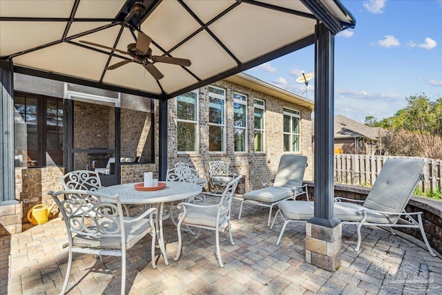 view of patio featuring ceiling fan, outdoor dining area, and fence