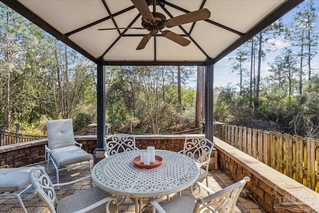 view of patio featuring a gazebo, ceiling fan, fence, and outdoor dining space