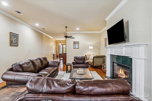 living room featuring visible vents, ornamental molding, wood finished floors, a fireplace, and recessed lighting