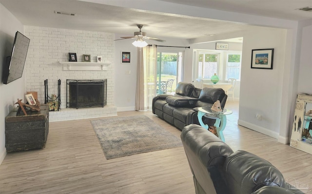 living room featuring ceiling fan, a fireplace, and light hardwood / wood-style flooring