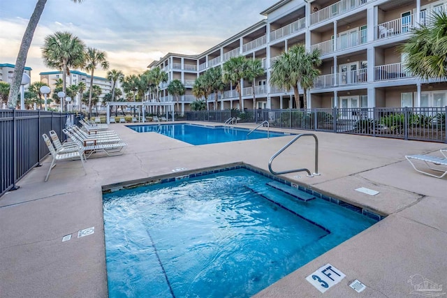 pool at dusk with a patio area