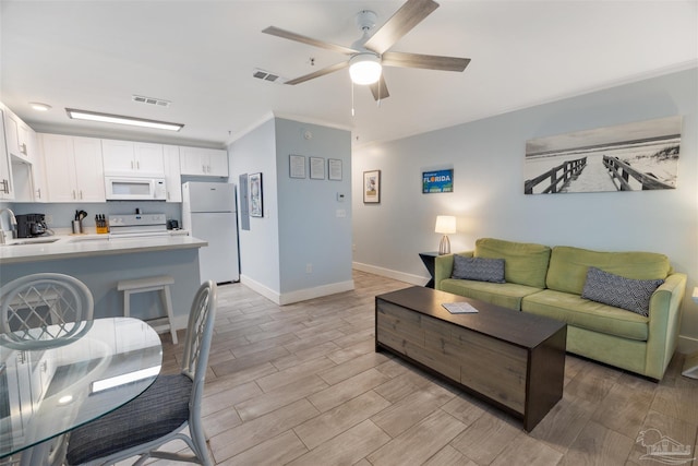 living room featuring crown molding, ceiling fan, sink, and light wood-type flooring