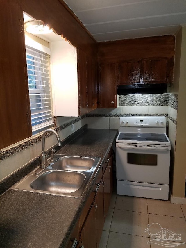 729 Lownde Ave, Pensacola, FL 32507 - kitchen featuring white electric range oven, a sink, under cabinet range hood, light tile patterned floors, and dark countertops