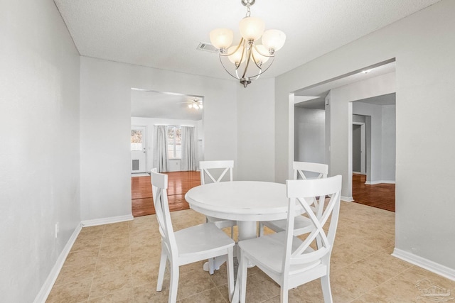 dining room featuring ceiling fan with notable chandelier and a textured ceiling