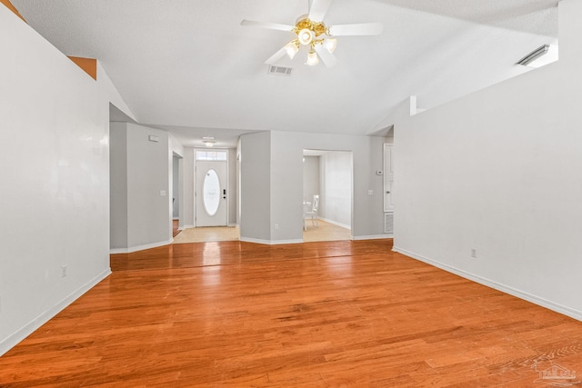 unfurnished living room featuring a textured ceiling, ceiling fan, light hardwood / wood-style floors, and vaulted ceiling