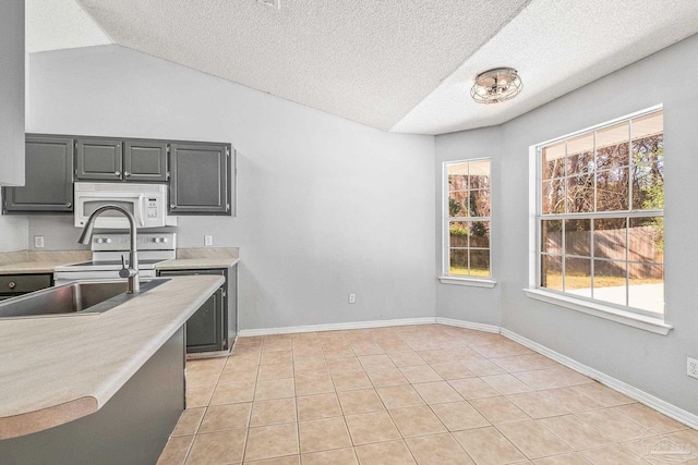 kitchen featuring sink, a textured ceiling, lofted ceiling, white appliances, and light tile patterned floors