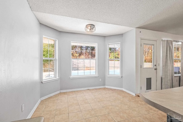 unfurnished dining area with light tile patterned flooring and a textured ceiling