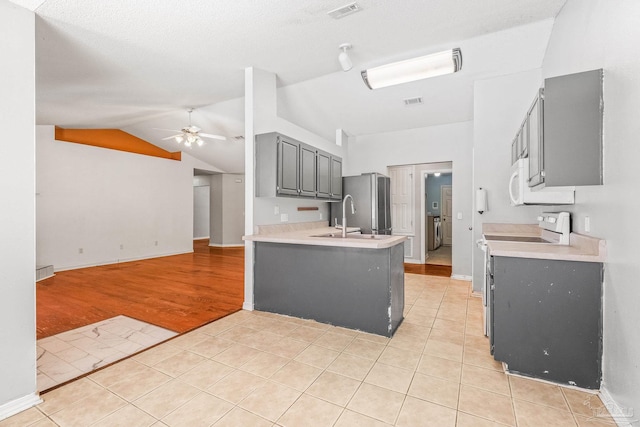 kitchen featuring kitchen peninsula, light tile patterned floors, gray cabinetry, and sink