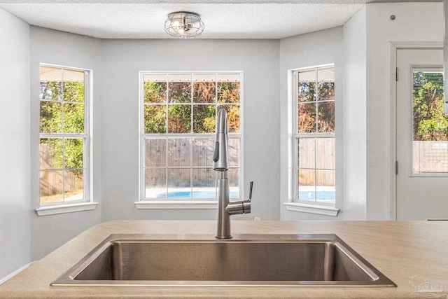 interior space with a textured ceiling, sink, and a wealth of natural light