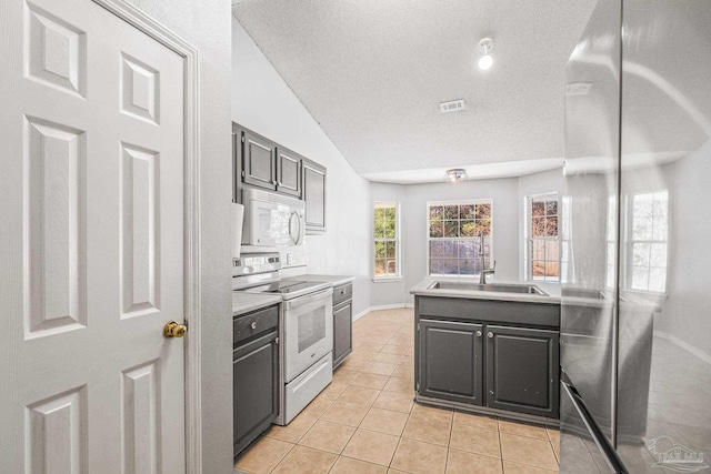 kitchen featuring sink, electric range oven, a textured ceiling, vaulted ceiling, and light tile patterned floors