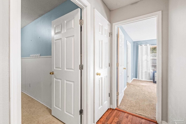 hall featuring light hardwood / wood-style floors and a textured ceiling