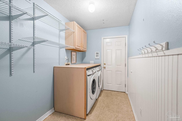 washroom with cabinets, independent washer and dryer, and a textured ceiling