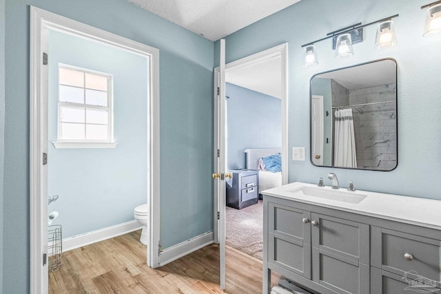 bathroom featuring vanity, hardwood / wood-style flooring, toilet, a textured ceiling, and curtained shower