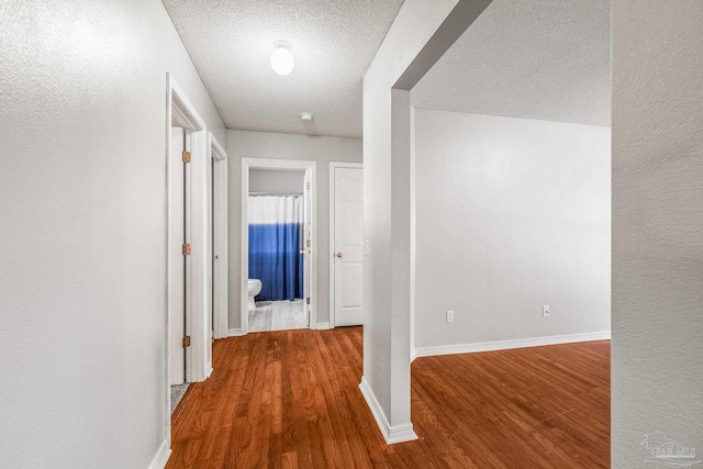 corridor featuring wood-type flooring and a textured ceiling