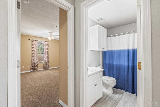 bathroom featuring ceiling fan, vanity, a textured ceiling, and toilet