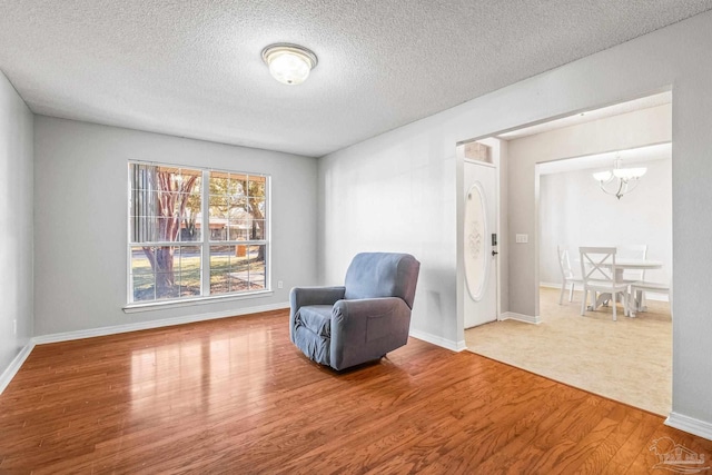 living area featuring a notable chandelier, a textured ceiling, and hardwood / wood-style flooring